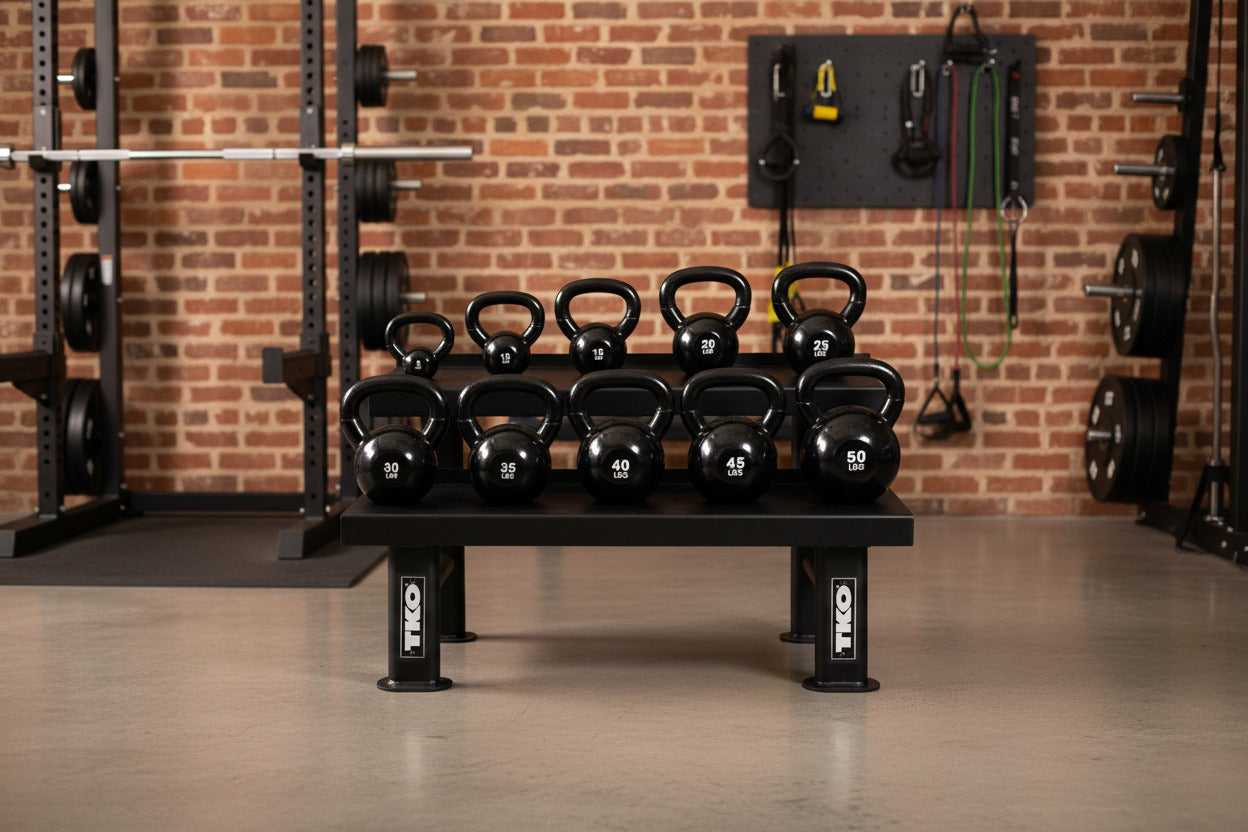 Gym setup with TKO 859KR-857KBV-BK kettlebells against a brick wall.