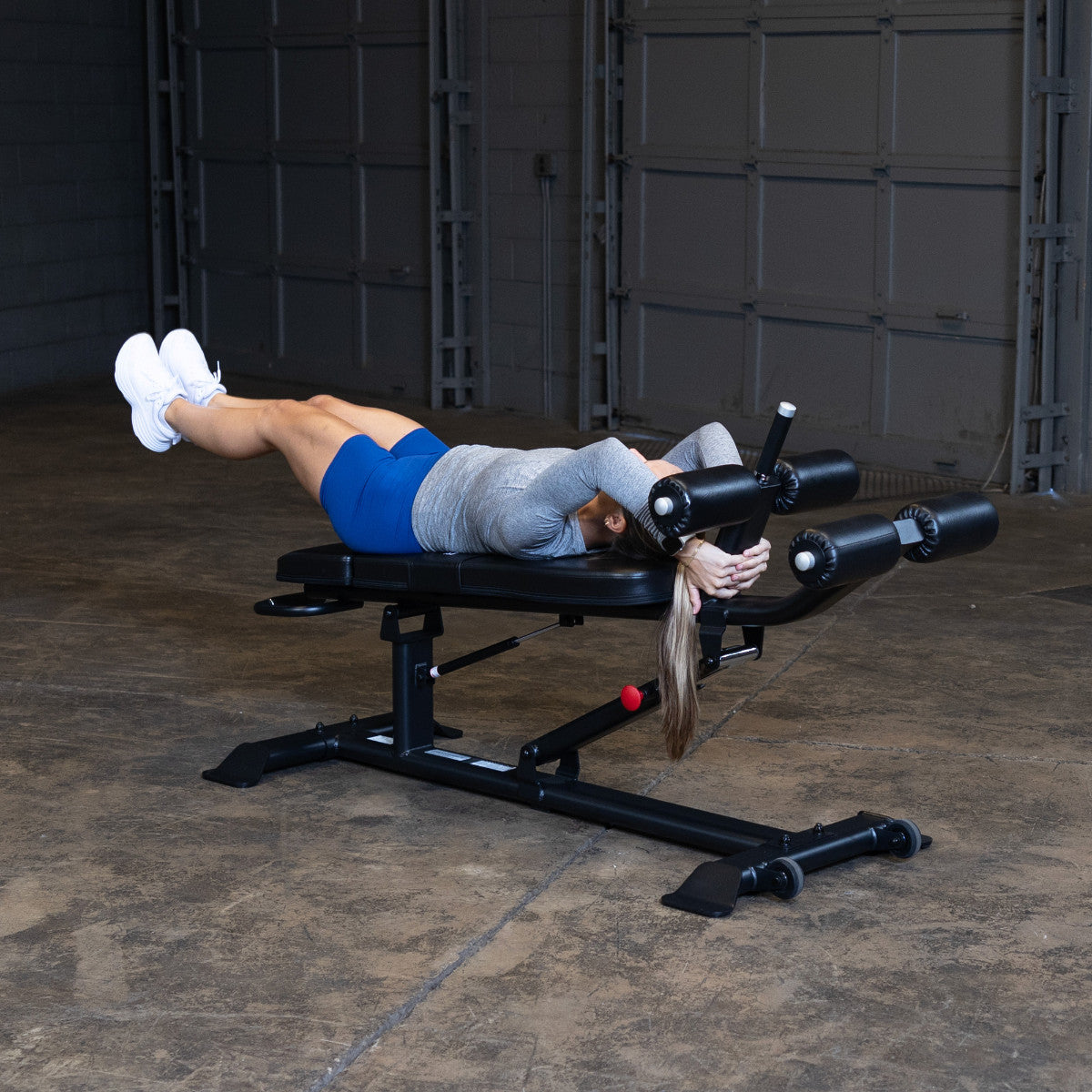 Body-Solid SAB500B Pro ClubLine Adjustable Decline Ab Bench in gym with woman doing leg lifts