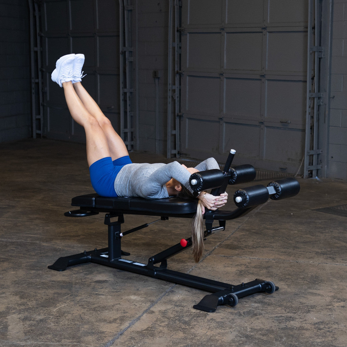 Body-Solid SAB500B Pro ClubLine Adjustable Decline Ab Bench in gym with woman doing leg lifts