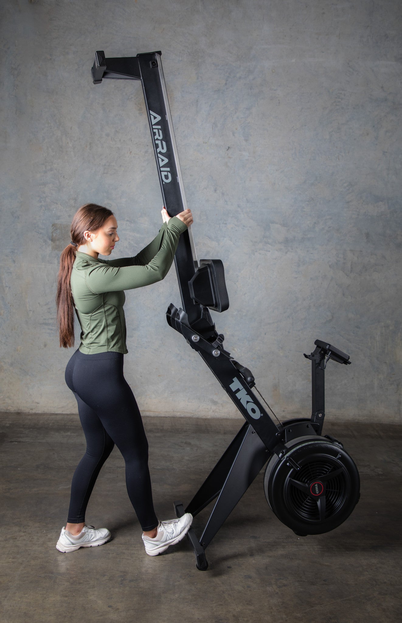 Woman standing up TKO 8AR AirRaid Rowing machine with a stand